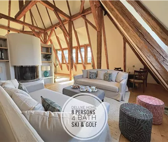 Ein geräumiges Wohnzimmer mit sichtbaren Holzstrahlen und gemütlichen Sofas. Der Raum ist hell und einladend, ideal für entspannte Aufenthalte.