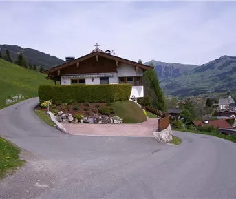 Ein charmantes Haus an einer kurvigen Straße in den Bergen. Die grüne Umgebung und die beeindruckende Aussicht schaffen eine idyllische Atmosphäre.