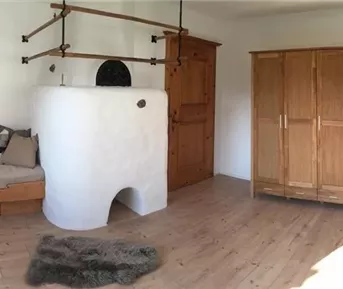 Ein gemütlicher Raum mit einem Holztag, einem Kamin und einem Fernseher. Die Wände sind hell und die Möbel haben einen rustikalen Stil.